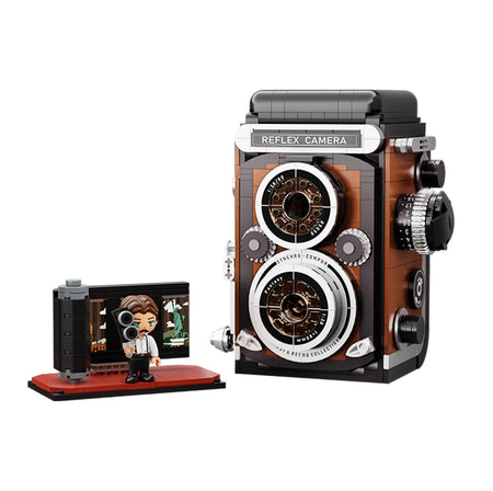 Brick model of a vintage camera with a smaller figure holding a camera, on a white background